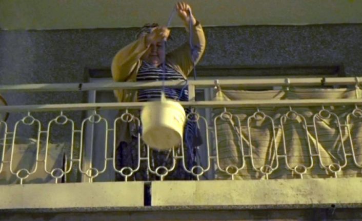 Her gün evinin balkonundan aşağı sarkıttığı kova ile sokak hayvanlarını besliyor