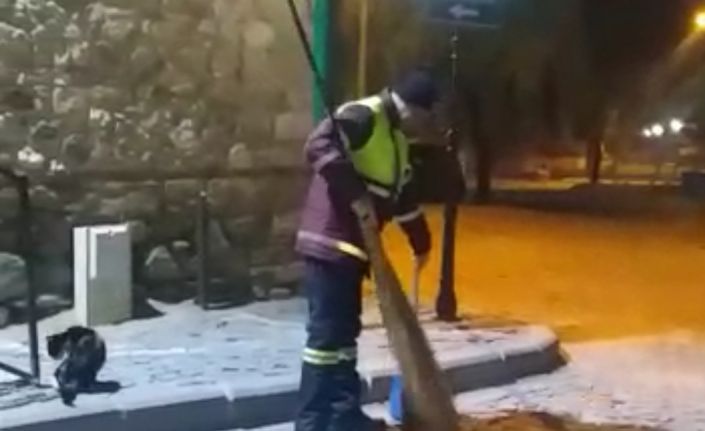 Hem çevreyi temizliyor hem de sokak kedisine süpürgesi ile masaj yapıyor