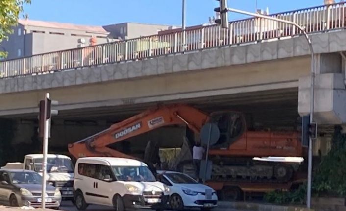 Tırın dorsesinde taşınan iş makinesi köprülü kavşakta üst geçide sıkıştı