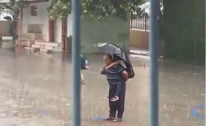 Dede torununu sırtına alarak yağmur altında İstiklal Marşı okudu