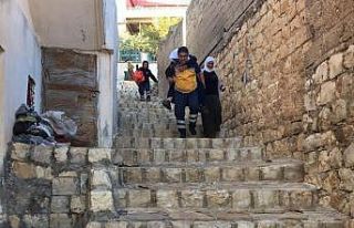 Sağlık görevlisi, yaşlı hastayı sırtına alarak...