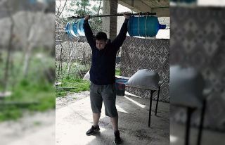 Genç kadın halterci, damacanadan yaptığı halter...