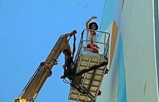 Kafasını kaldırıp vincin tepesinde elinde fırçayla...