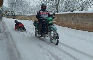 Motosiklete bağladığı kızaklarla çocukları...