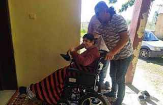 Fiziksel engelli genç kadın akülü tekerlekli sandalyesine...