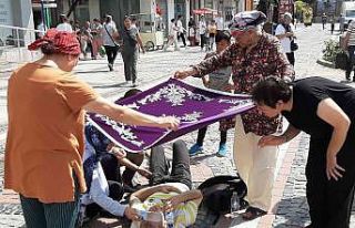 Kadınlar yerde yatan yaralıyı örtü ile güneşten...