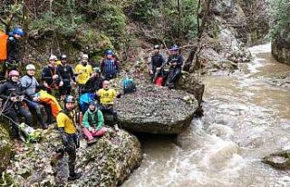 Yağmur ve kar sularıyla coşan kanyonu geçen sporcu...